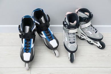 Photo of Pairs of roller skates on floor near white wall
