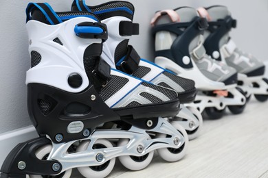 Photo of Pairs of roller skates on floor near white wall, closeup