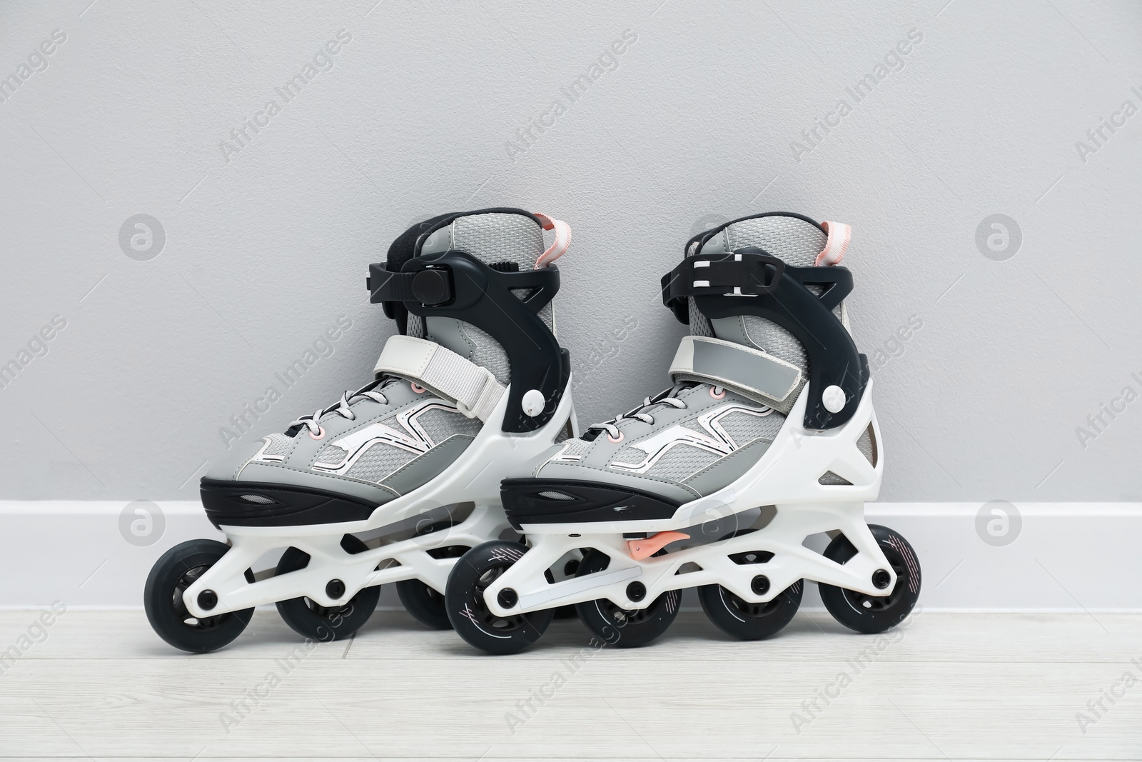 Pair of roller skates on floor near white wall Photo of Pair of roller skates on floor near white wall