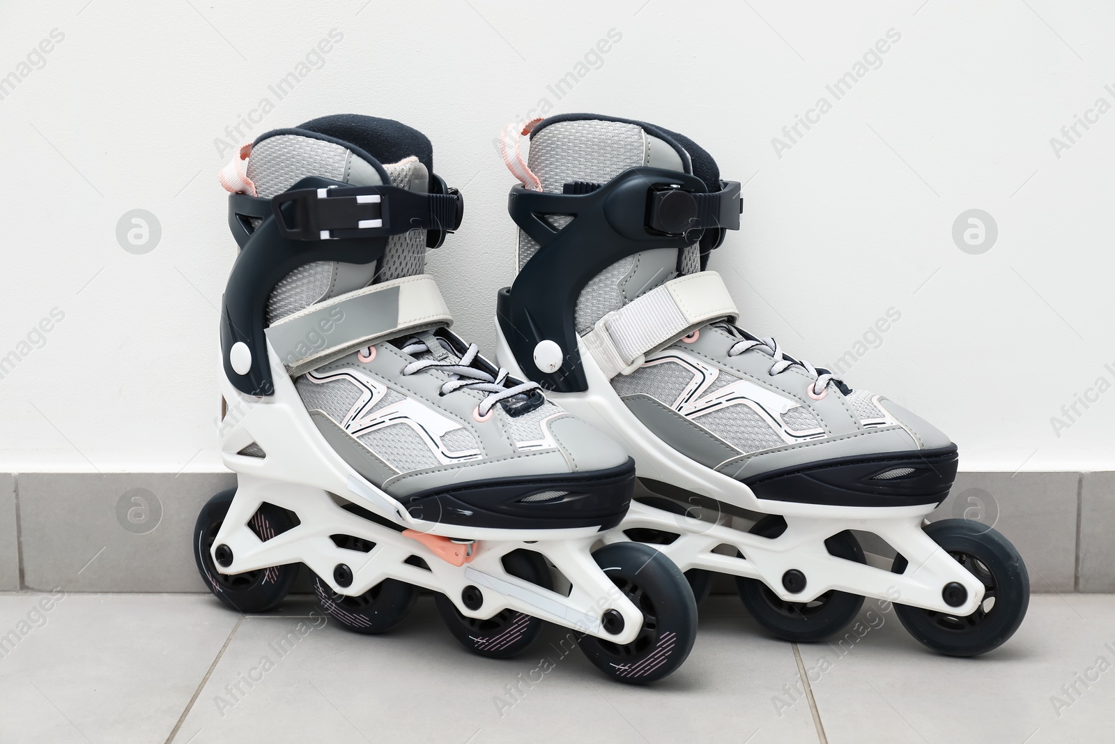 Pair of roller skates on floor near white wall Photo of Pair of roller skates on floor near white wall
