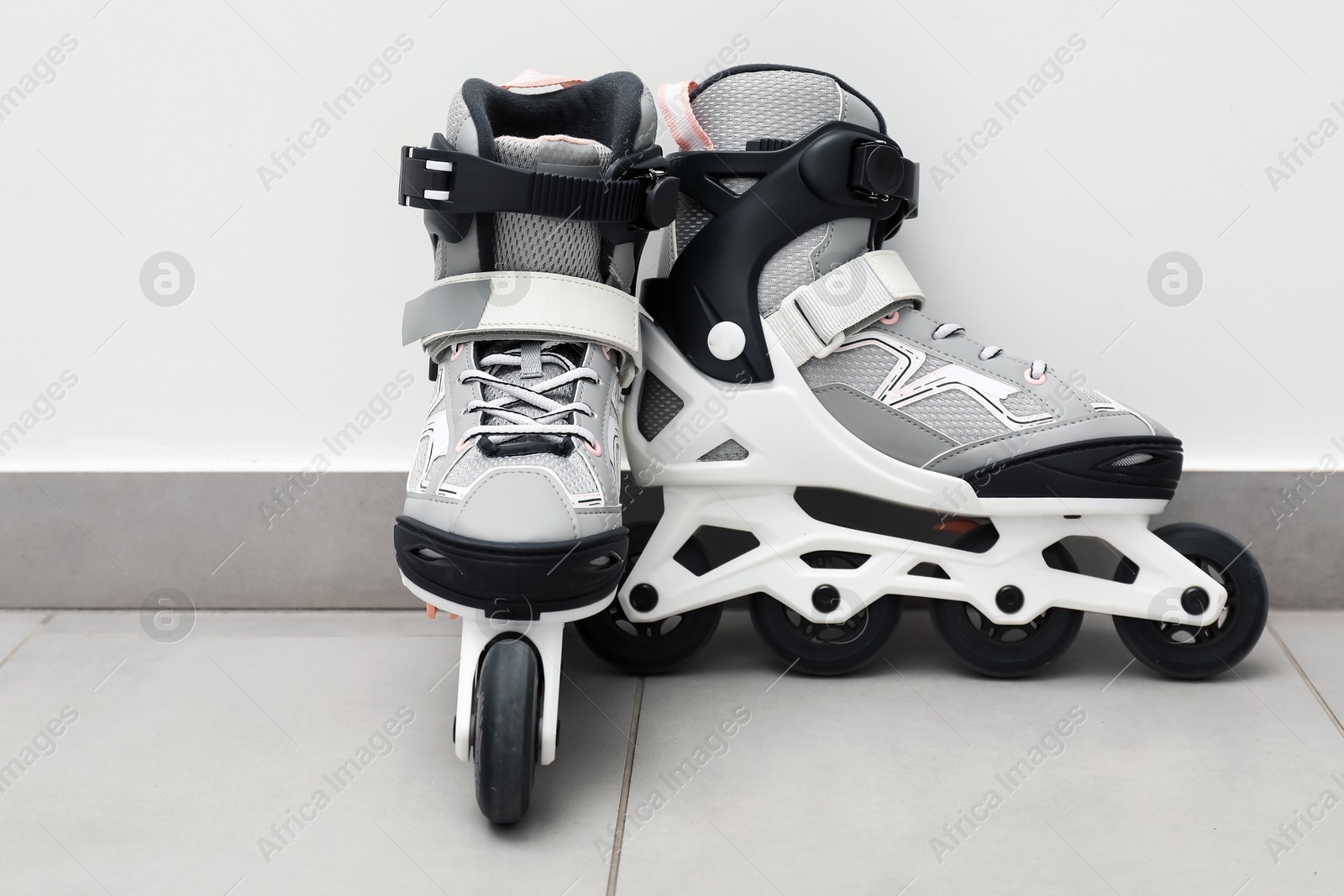 Pair of roller skates on floor near white wall Photo of Pair of roller skates on floor near white wall