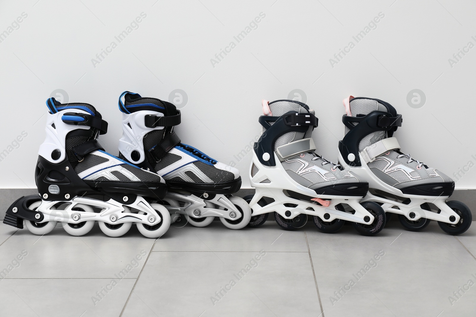 Pairs of roller skates on floor near white wall Photo of Pairs of roller skates on floor near white wall