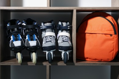 Photo of Pairs of roller skates and backpack in shelving unit, closeup
