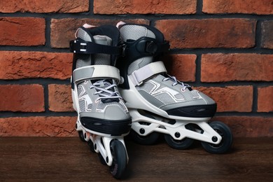 Photo of Pair of roller skates on wooden table near brick wall