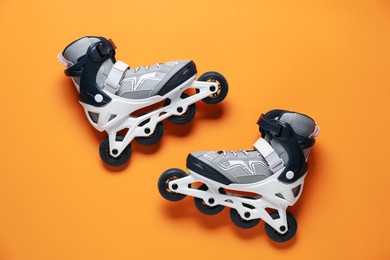 Photo of Pair of roller skates on orange background, top view