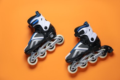 Photo of Pair of roller skates on orange background, top view