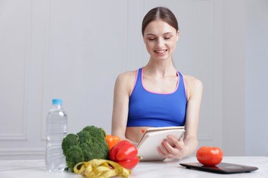 Photo of Woman developing diet plan at white marble table indoors