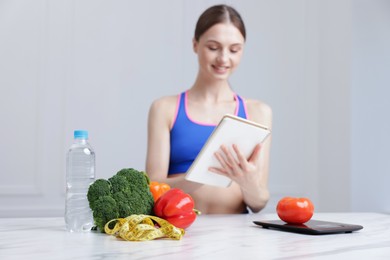 Photo of Woman developing diet plan at white marble table indoors, selective focus