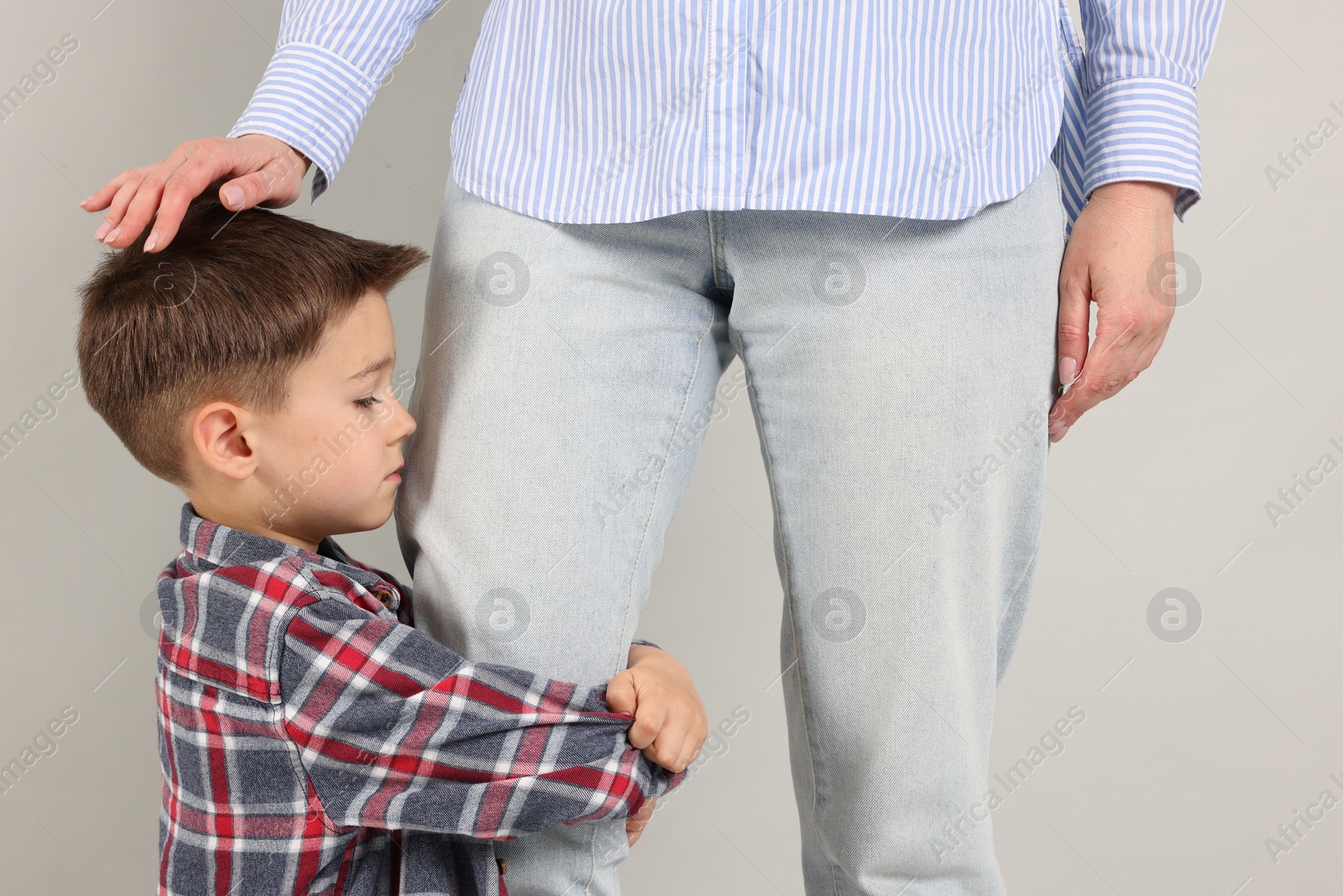 Little boy afraid to leave without mother and hugging her on grey background. Separation anxiety Photo of Little boy afraid to leave without mother and hugging her on grey background. Separation anxiety