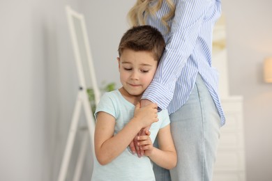Photo of Little boy afraid to leave without mother and holding hands with her at home. Separation anxiety