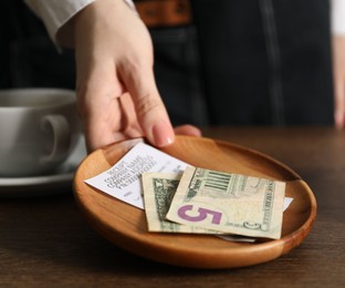 Photo of Waitress taking tips from wooden table in cafe, closeup