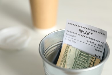 Photo of Tips and receipt in metal bucket on white table, closeup. Space for text