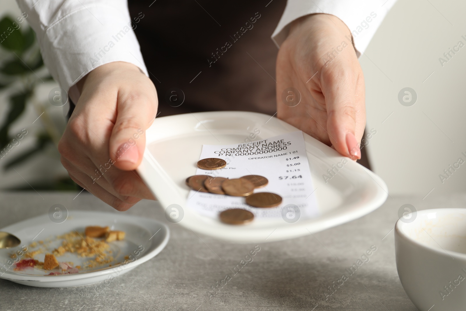 Waitress taking tips from grey table in cafe, closeup Photo of Waitress taking tips from grey table in cafe, closeup