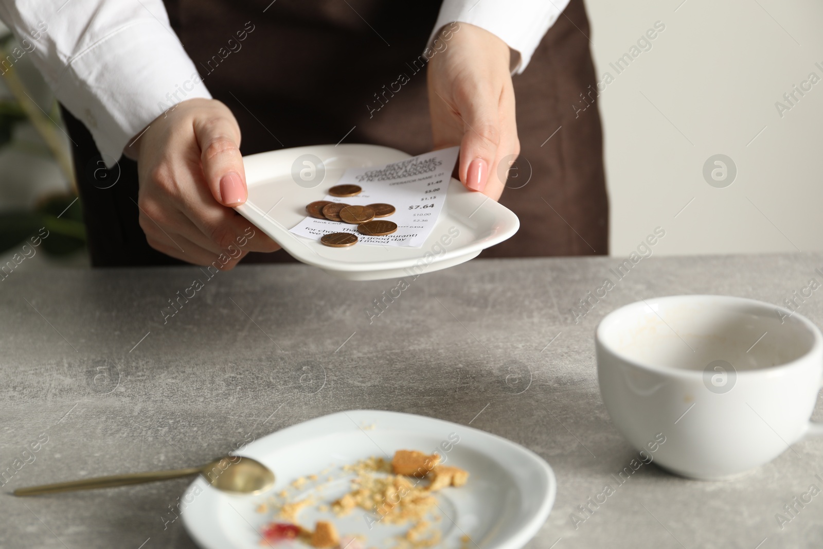 Waitress taking tips from grey table in cafe, closeup Photo of Waitress taking tips from grey table in cafe, closeup