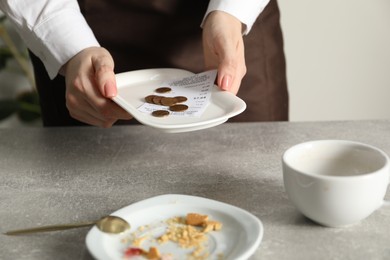 Photo of Waitress taking tips from grey table in cafe, closeup