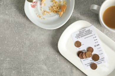 Photo of Tips, receipt, dirty plate and cup on grey table, flat lay. Space for text