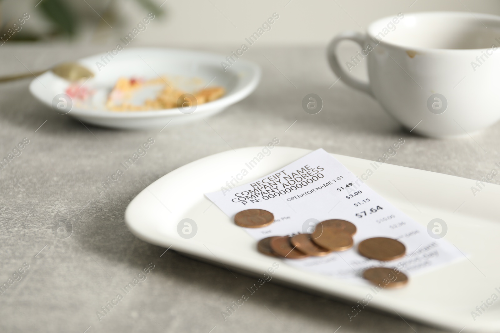 Tips, receipt, dirty plate and cup on grey table in cafe, closeup Photo of Tips, receipt, dirty plate and cup on grey table in cafe, closeup