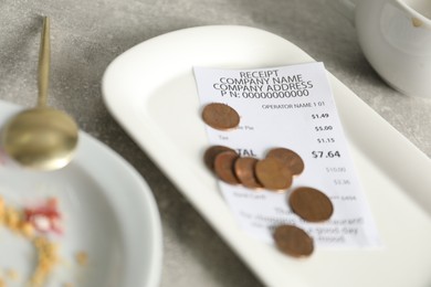 Photo of Tips, receipt and dirty plate on grey table, closeup