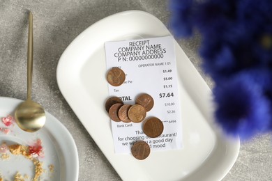 Photo of Tips, receipt and dirty plate on grey table, flat lay