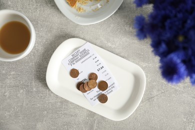 Photo of Tips, receipt, dirty plate and cup on grey table, flat lay