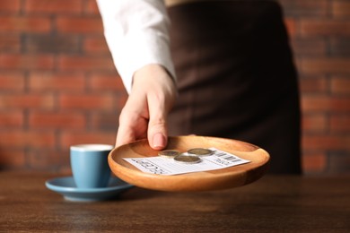 Photo of Waitress taking tips from wooden table in cafe, closeup
