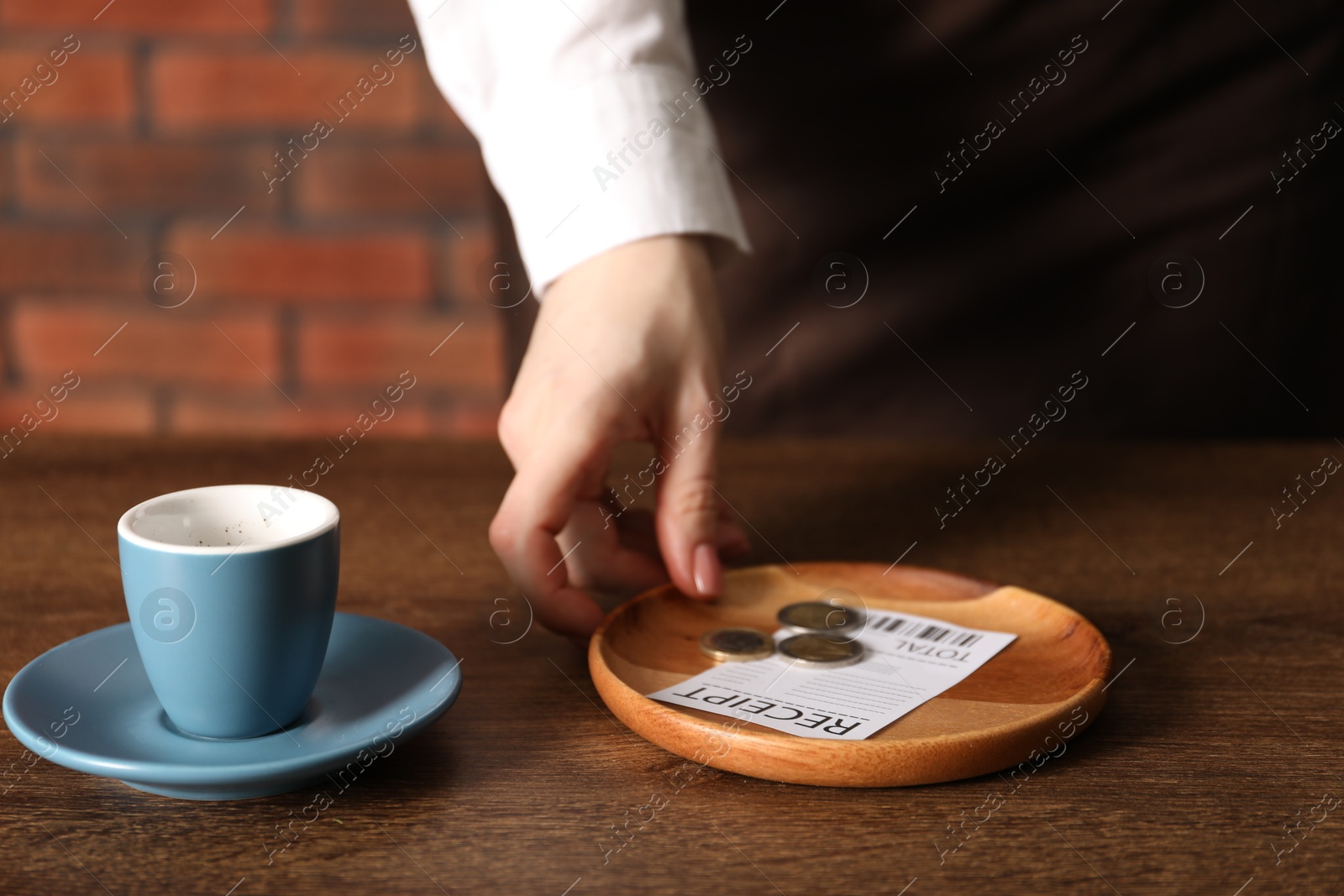 Waitress taking tips from wooden table in cafe, closeup Photo of Waitress taking tips from wooden table in cafe, closeup