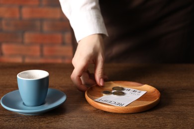 Photo of Waitress taking tips from wooden table in cafe, closeup