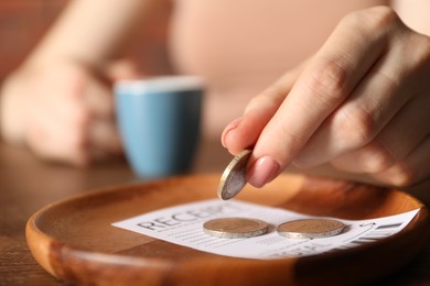 Photo of Woman putting tips onto plate at table in cafe, closeup