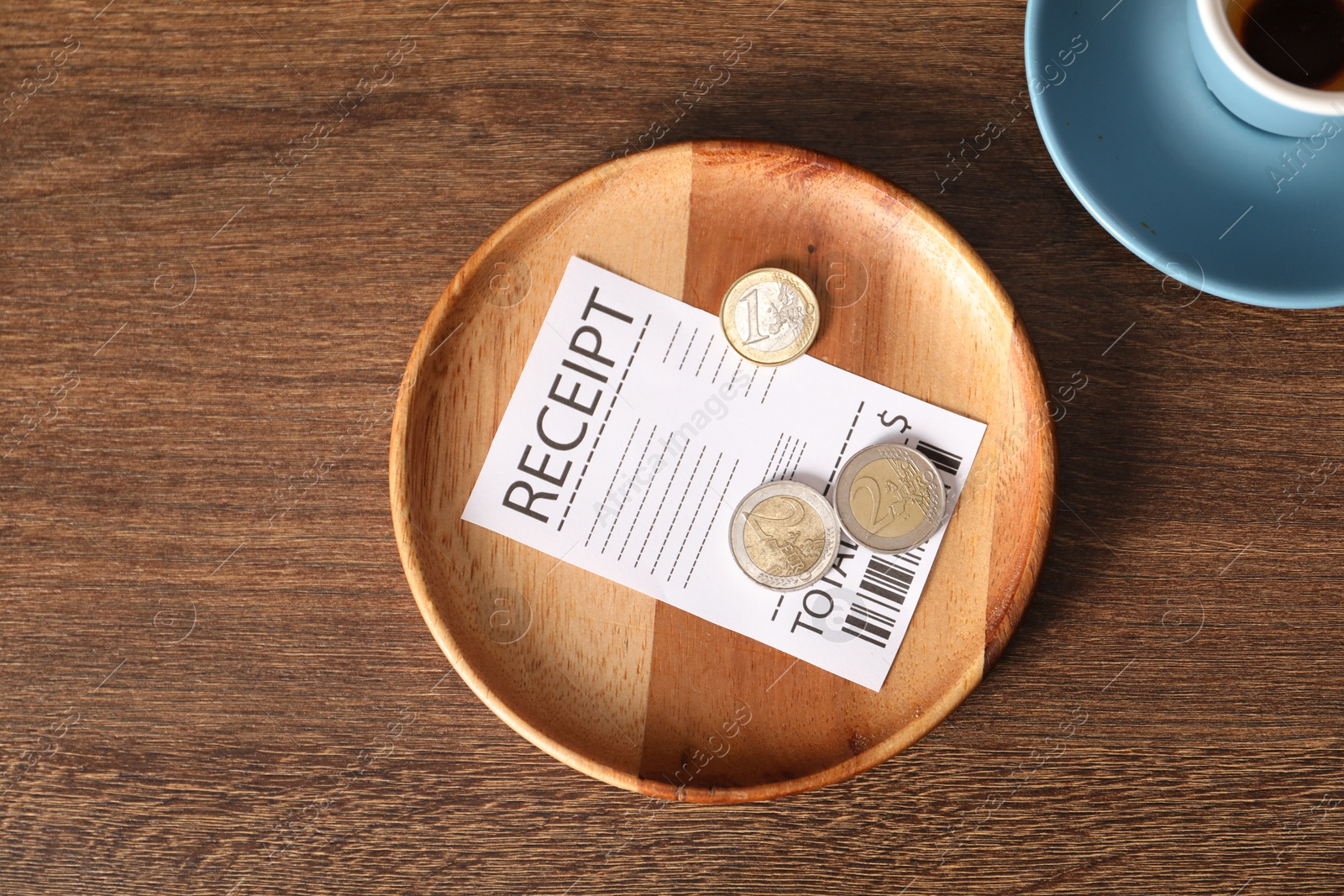 Photo of Tips, receipt and dirty cup on wooden table, flat lay