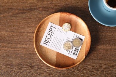 Photo of Tips, receipt and dirty cup on wooden table, flat lay