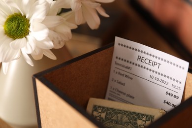 Photo of Tips, receipt and chrysanthemum flowers in cafe, closeup