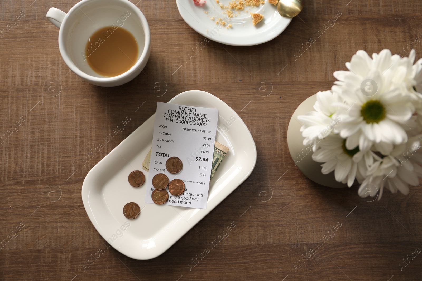 Tips, receipt, dirty plate, cup and flowers on wooden table, flat lay Photo of Tips, receipt, dirty plate, cup and flowers on wooden table, flat lay