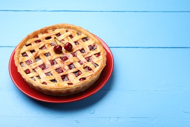 Photo of Tasty cherry pie on light blue wooden table, space for text