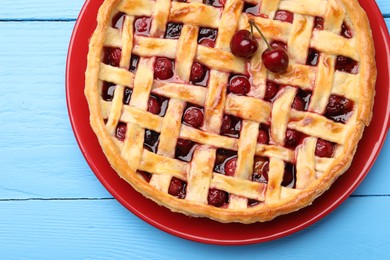 Photo of Tasty cherry pie on light blue wooden table, top view