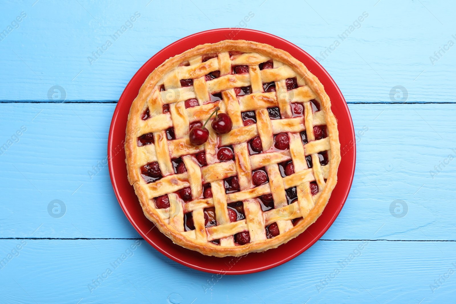 Photo of Tasty cherry pie on light blue wooden table, top view