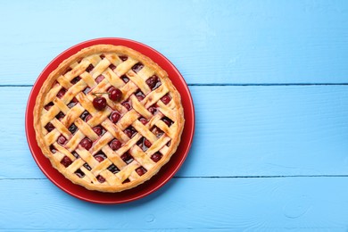 Photo of Tasty cherry pie on light blue wooden table, top view. Space for text