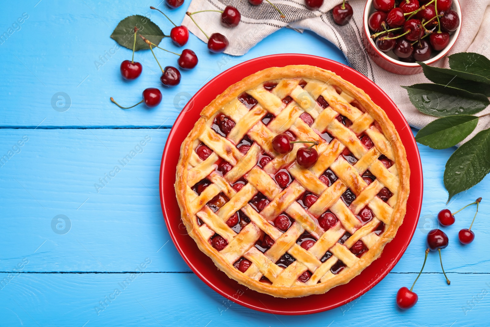 Photo of Tasty cherry pie and berries on light blue wooden table, flat lay