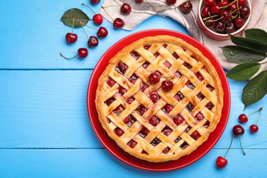 Photo of Tasty cherry pie and berries on light blue wooden table, flat lay