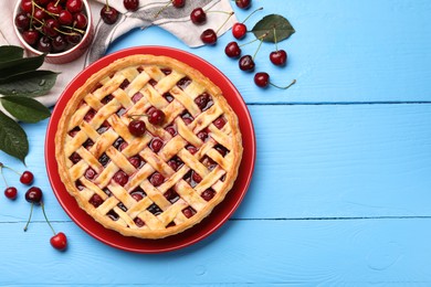 Photo of Tasty cherry pie and berries on light blue wooden table, flat lay. Space for text