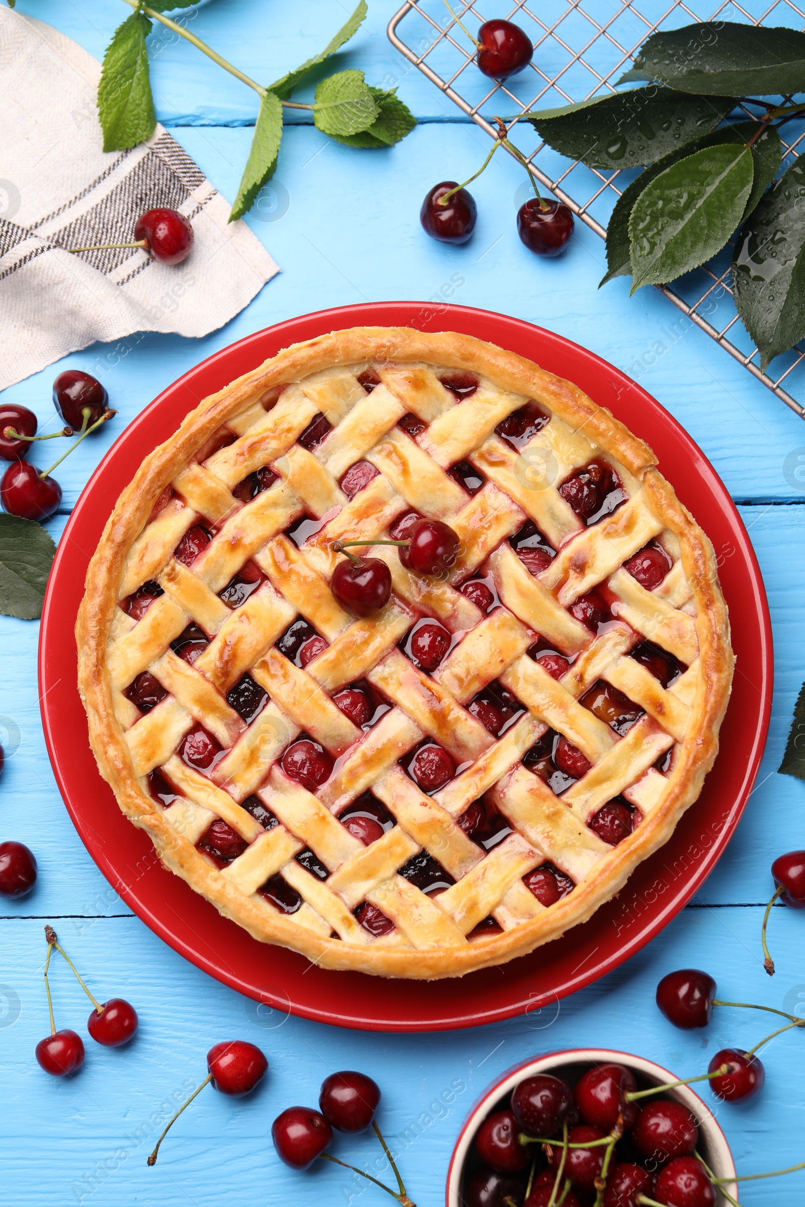 Photo of Tasty cherry pie and berries on light blue wooden table, flat lay
