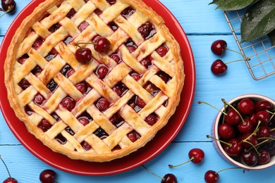 Photo of Tasty cherry pie and berries on light blue wooden table, flat lay