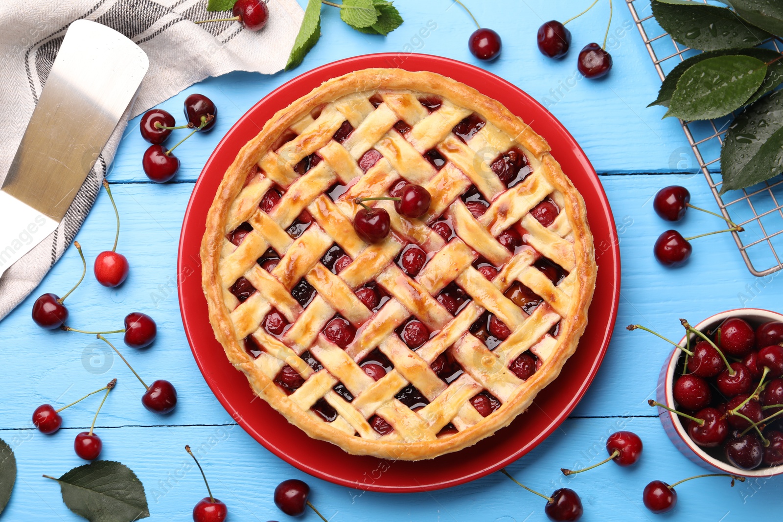 Photo of Tasty cherry pie and berries on light blue wooden table, flat lay