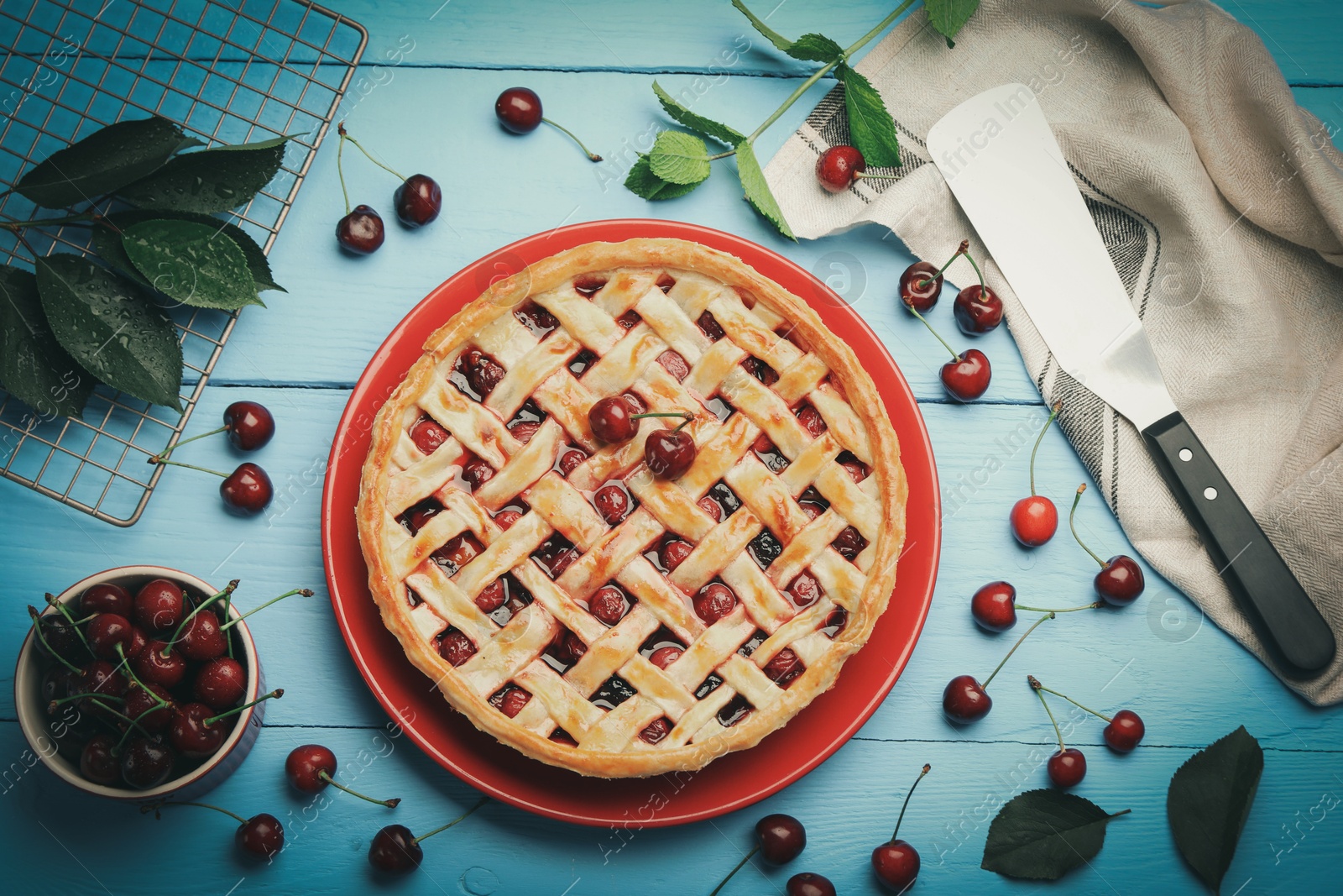 Photo of Tasty cherry pie and berries on light blue wooden table, flat lay