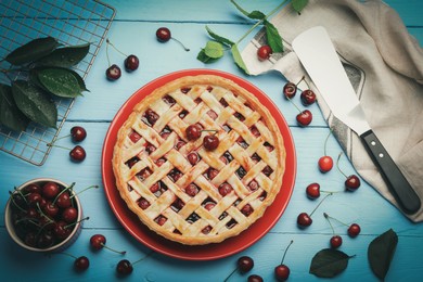 Photo of Tasty cherry pie and berries on light blue wooden table, flat lay