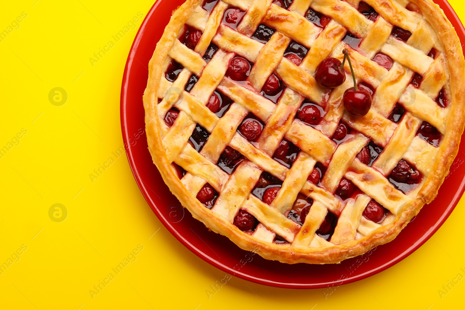 Tasty cherry pie on yellow background, top view Photo of Tasty cherry pie on yellow background, top view