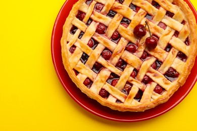 Photo of Tasty cherry pie on yellow background, top view