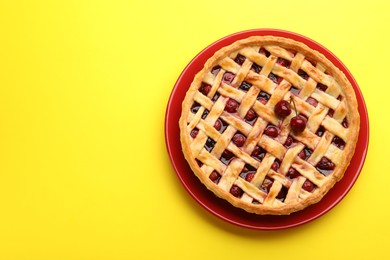Photo of Tasty cherry pie on yellow background, top view