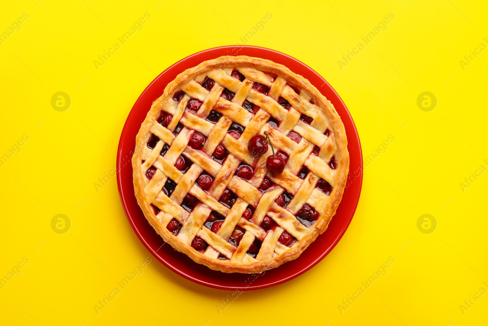 Photo of Tasty cherry pie on yellow background, top view
