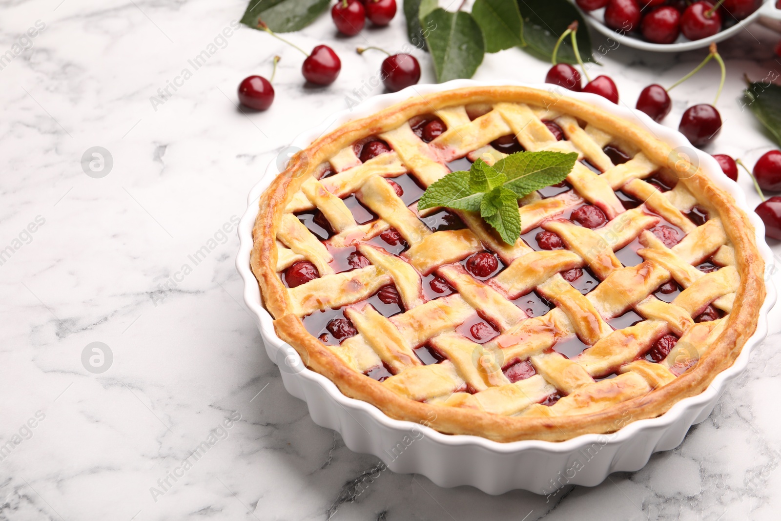 Photo of Tasty cherry pie and berries on white marble table, closeup. Space for text