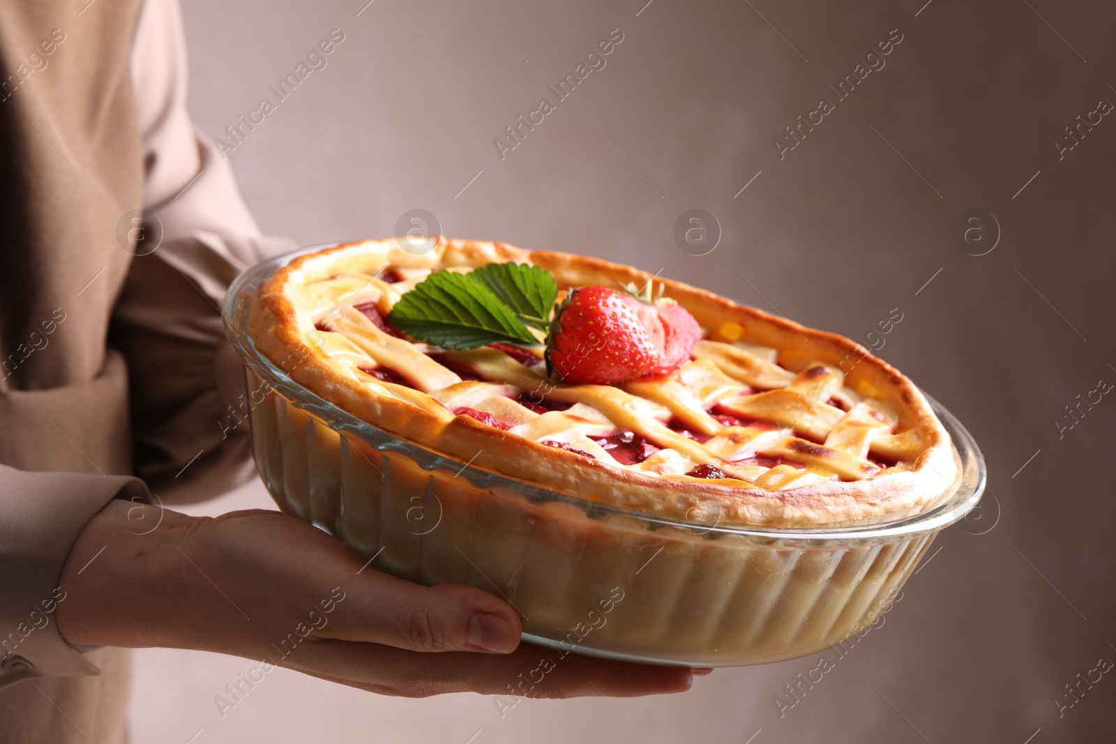 Woman holding tasty strawberry pie on light brown background, closeup Photo of Woman holding tasty strawberry pie on light brown background, closeup